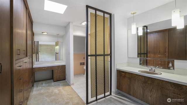 bathroom featuring a skylight, tile patterned flooring, vanity, and toilet