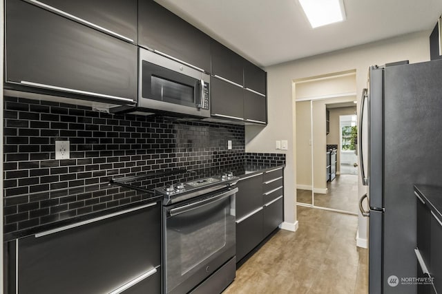 kitchen with tasteful backsplash, appliances with stainless steel finishes, and light hardwood / wood-style floors