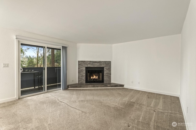 unfurnished living room featuring a stone fireplace and carpet floors