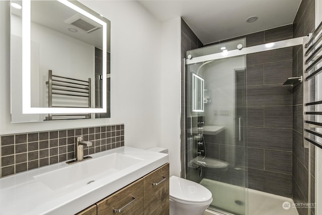 bathroom featuring radiator, a shower with shower door, backsplash, vanity, and toilet