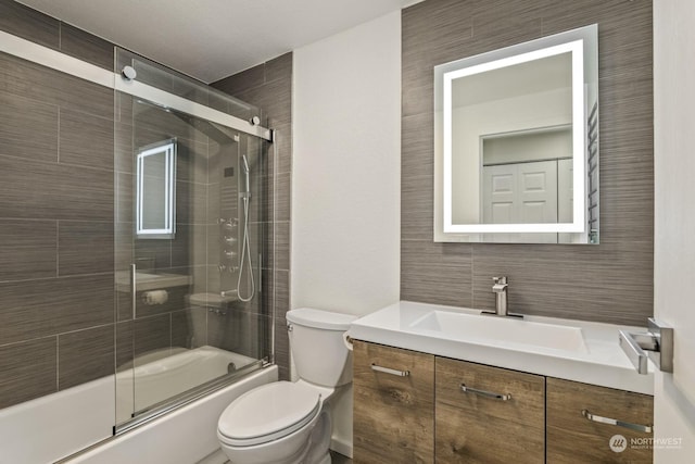 full bathroom with vanity, shower / bath combination with glass door, and toilet