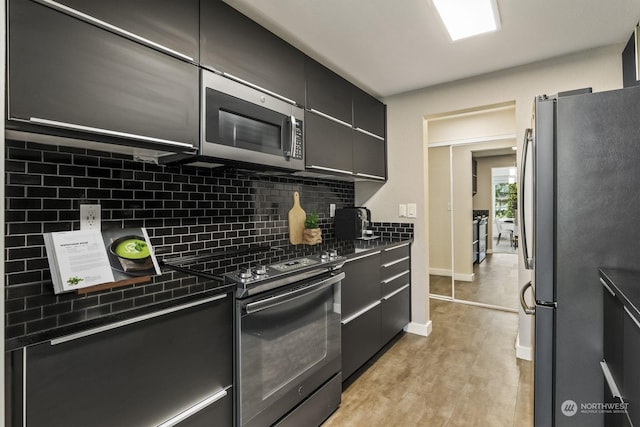 kitchen with appliances with stainless steel finishes, backsplash, and light hardwood / wood-style flooring