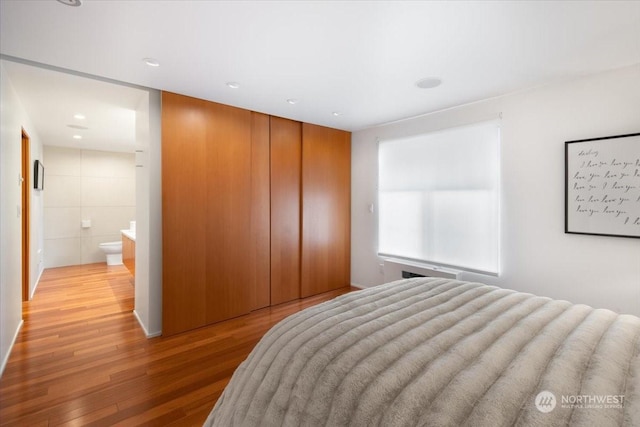 bedroom featuring connected bathroom, hardwood / wood-style flooring, and a closet