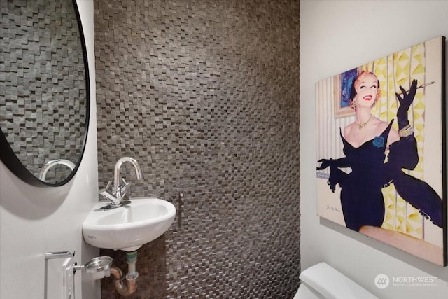 bathroom featuring toilet, sink, and tasteful backsplash