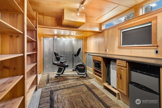 exercise room with track lighting and wood walls