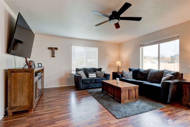 living room featuring a textured ceiling, ceiling fan, and dark wood-type flooring