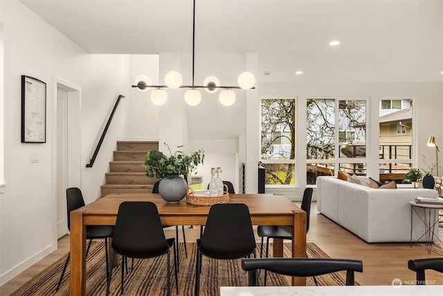 dining room with light wood-type flooring and an inviting chandelier