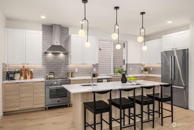 kitchen with white cabinets, wall chimney range hood, sink, and appliances with stainless steel finishes