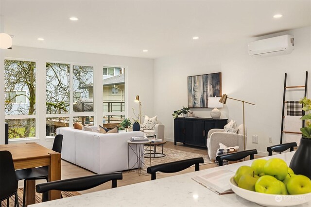 living room with a wall mounted air conditioner and light wood-type flooring