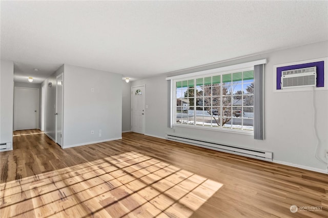 unfurnished room with a baseboard radiator, a wall mounted air conditioner, and wood-type flooring