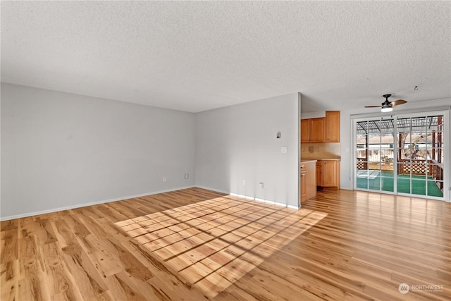 unfurnished living room featuring ceiling fan, light hardwood / wood-style floors, and a textured ceiling