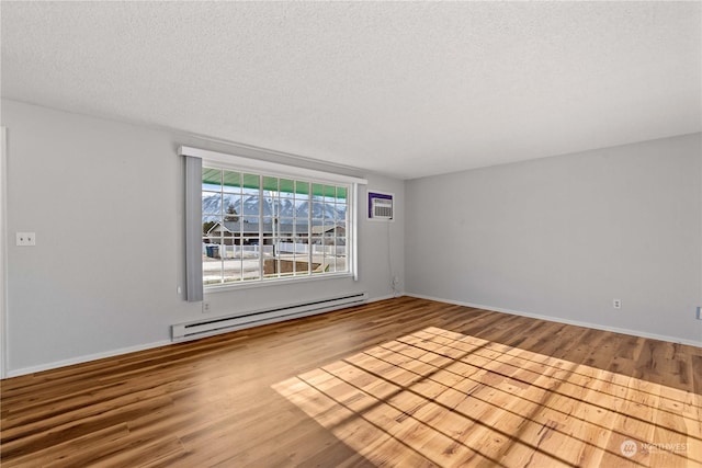 empty room featuring a textured ceiling, an AC wall unit, light hardwood / wood-style flooring, and a baseboard radiator