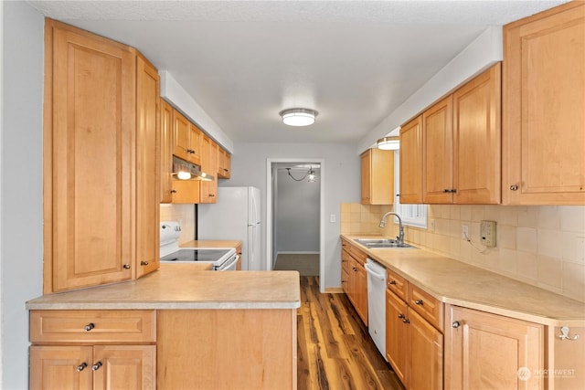 kitchen featuring kitchen peninsula, dark hardwood / wood-style flooring, tasteful backsplash, white appliances, and sink