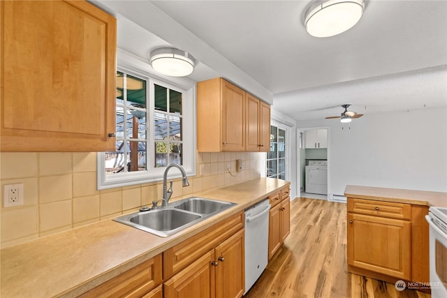 kitchen featuring tasteful backsplash, sink, dishwasher, washer / dryer, and light hardwood / wood-style floors