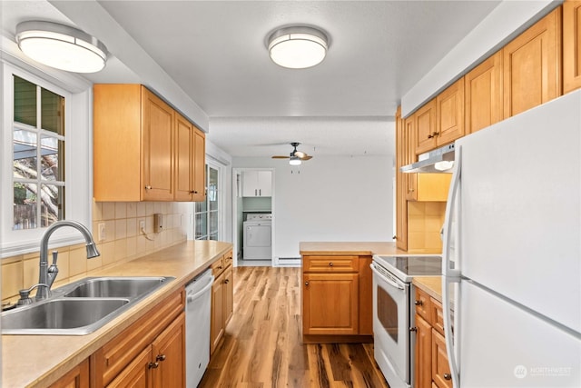 kitchen with white appliances, backsplash, sink, plenty of natural light, and washer / dryer