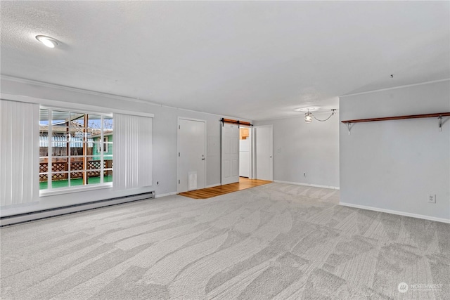 spare room with light carpet, a textured ceiling, a barn door, and a baseboard radiator