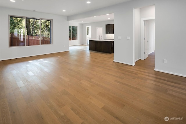 unfurnished living room with sink and light wood-type flooring