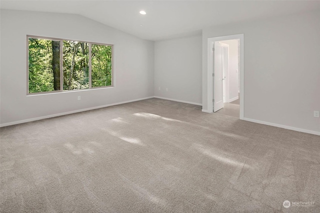 unfurnished room featuring light carpet and vaulted ceiling