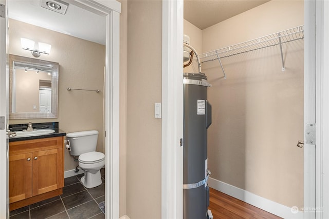 bathroom featuring tile patterned flooring, vanity, toilet, and strapped water heater