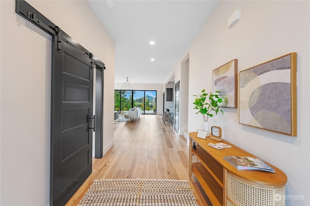 hall featuring a barn door and light hardwood / wood-style flooring