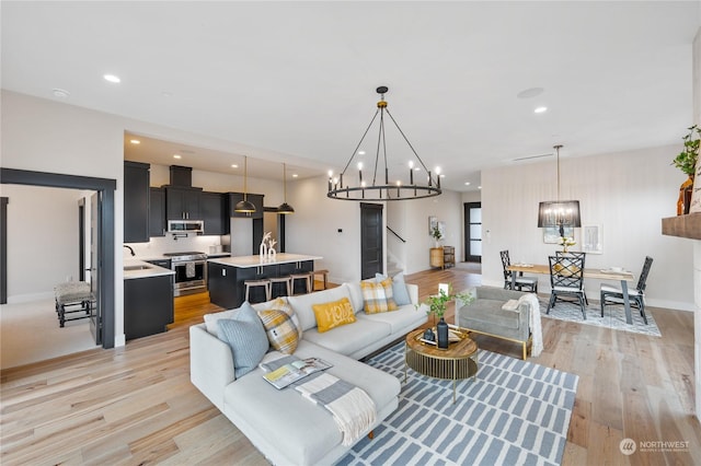 living room with sink, light hardwood / wood-style floors, and an inviting chandelier