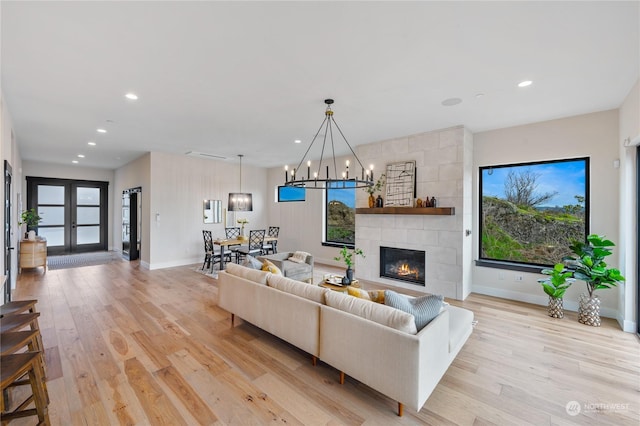 living room with a tiled fireplace, light hardwood / wood-style flooring, and plenty of natural light