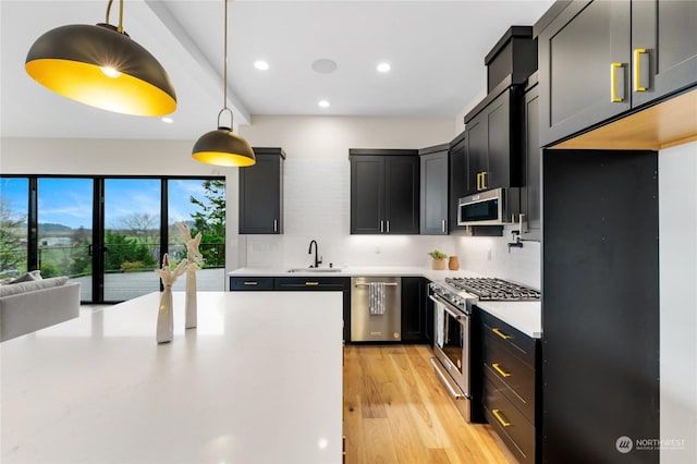 kitchen featuring pendant lighting, decorative backsplash, sink, and appliances with stainless steel finishes