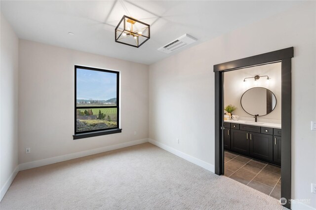 unfurnished room with a chandelier, light colored carpet, and sink