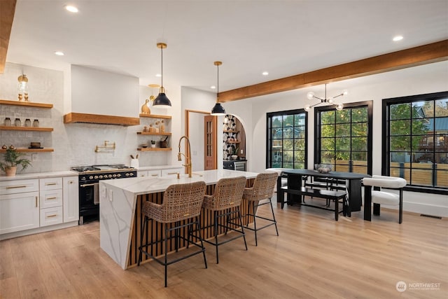 kitchen featuring a kitchen breakfast bar, range with two ovens, pendant lighting, decorative backsplash, and white cabinetry