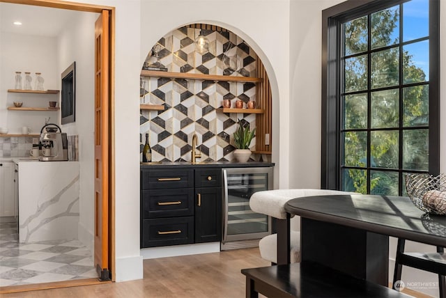 bar with white cabinets, wine cooler, and light hardwood / wood-style flooring