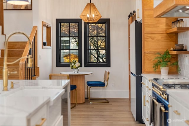 kitchen featuring high end range, white cabinetry, black refrigerator, hanging light fixtures, and a barn door