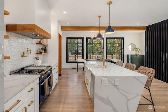 kitchen with range with two ovens, white cabinetry, light stone countertops, and premium range hood