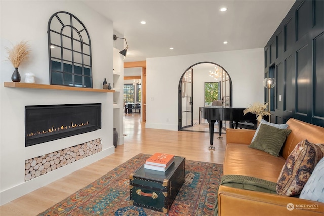 living room featuring a large fireplace, a notable chandelier, and light hardwood / wood-style flooring