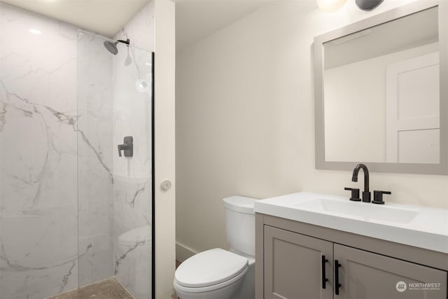 bathroom with toilet, tiled shower, and vanity