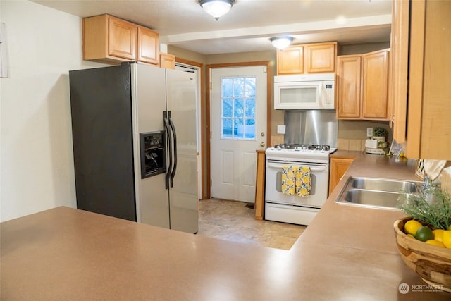 kitchen with light brown cabinetry, white appliances, and sink