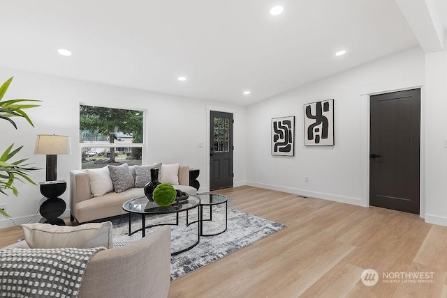 living room with light hardwood / wood-style floors and vaulted ceiling