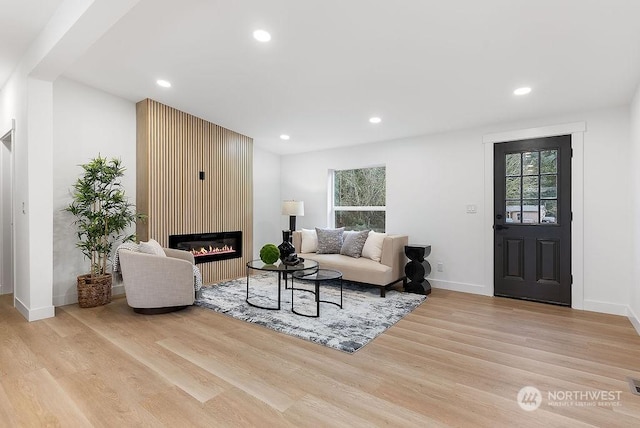 living room with a large fireplace, plenty of natural light, and light hardwood / wood-style floors