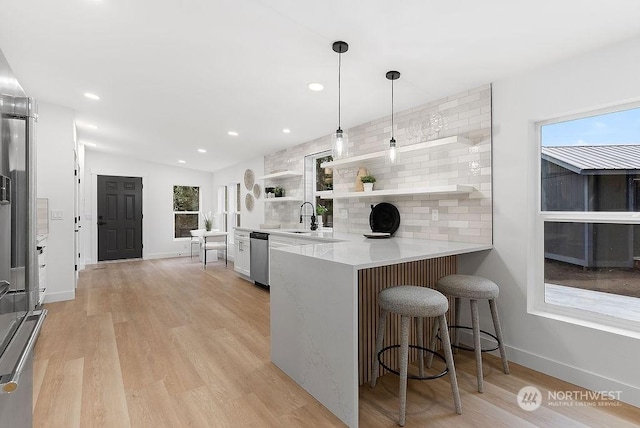 kitchen with pendant lighting, a breakfast bar, lofted ceiling, appliances with stainless steel finishes, and kitchen peninsula