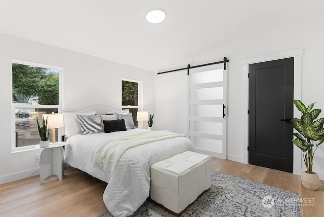 bedroom featuring a barn door and light hardwood / wood-style flooring