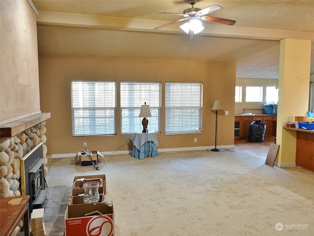 interior space with ceiling fan, a fireplace, beamed ceiling, and carpet flooring