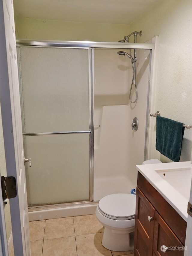 bathroom featuring an enclosed shower, vanity, tile patterned flooring, and toilet