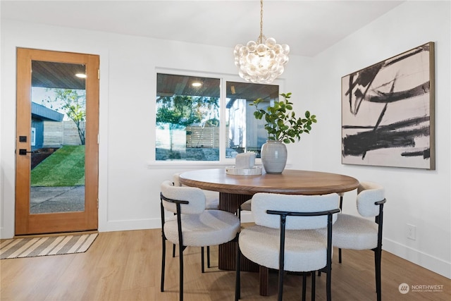 dining room with light wood-type flooring and an inviting chandelier