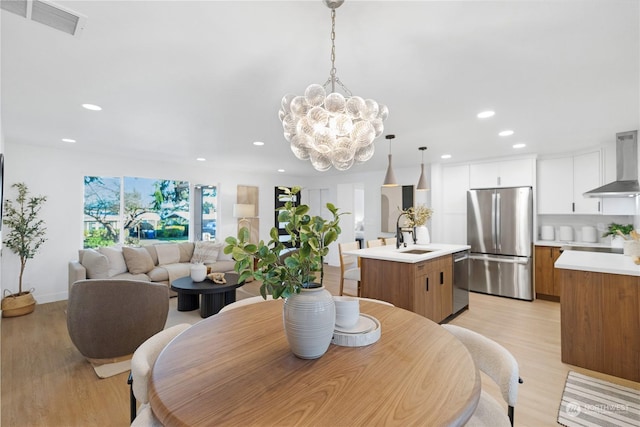 dining space featuring light hardwood / wood-style floors, an inviting chandelier, and sink