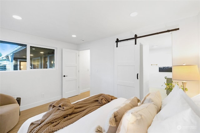 bedroom featuring a barn door and light wood-type flooring