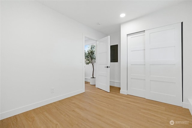 unfurnished bedroom featuring light wood-type flooring, electric panel, and a closet