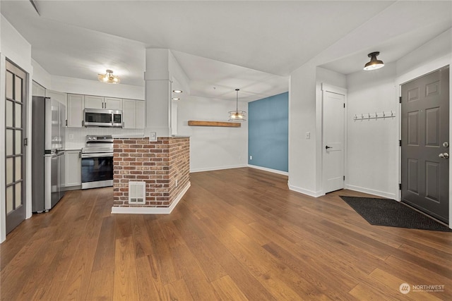 kitchen featuring wood-type flooring, stainless steel appliances, pendant lighting, white cabinets, and backsplash