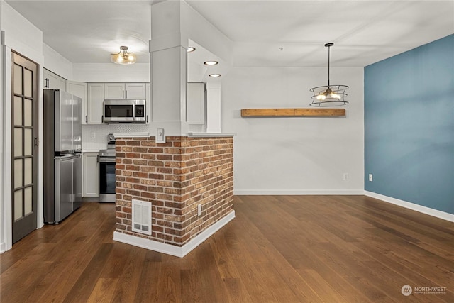 kitchen with appliances with stainless steel finishes, dark hardwood / wood-style floors, hanging light fixtures, and decorative backsplash