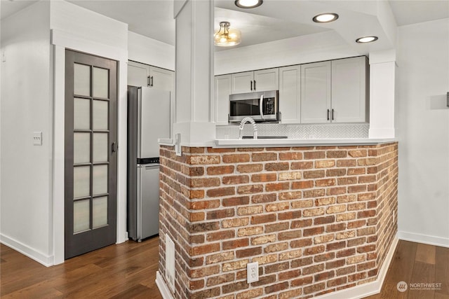 kitchen featuring stainless steel appliances, decorative backsplash, gray cabinets, and dark hardwood / wood-style floors