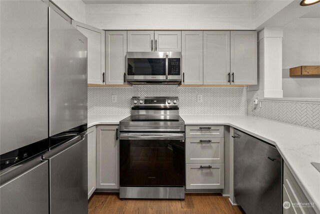 kitchen with stainless steel appliances, light hardwood / wood-style flooring, gray cabinets, and decorative backsplash