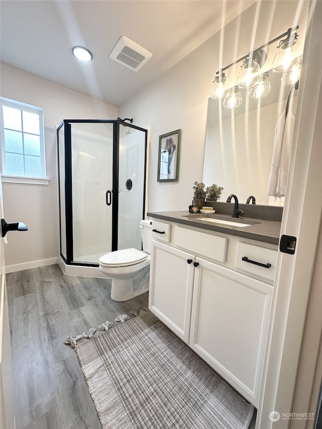 bathroom with wood-type flooring, toilet, a shower with shower door, and vanity